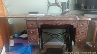 Full view of the sewing machine set in wooden table with seven drawers and cast iron treadle base.