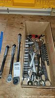 Top view showing three ratchet wrenches alongside a box containing multiple socket sizes, combination wrenches and Allen wrenches.