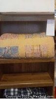 Yellow patchwork quilt folded on wooden shelf