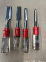 Full view of four Stanley chisels arranged in a row, showing different blade sizes and clear handles with red accents.