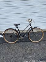 Side profile of unrestored black Raleigh Sport women's bicycle with tan tires and brown leather saddle.