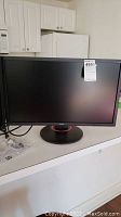 Front view of Acer monitor powered off, showing screen and attached cables on counter.