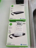 Photo showing both boxed adapters with MaxSold labeling, identifying the lot as two Belkin Thunderbolt Dock Mini adapters