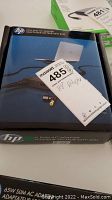 Front and top view of sealed retail box for HP 65W slim AC adapter showing brand, wattage, and product image.