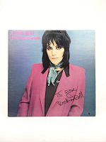 Front cover of Joan Jett and the Blackhearts 12" vinyl LP, showing Joan Jett in a pink jacket with a blue scarf and black shirt.