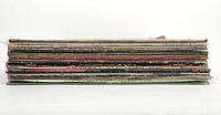 Side view of 12 LP vinyl record soundtrack albums stacked horizontally showing spines and wear on covers.