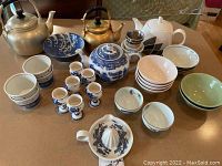 Overview photo of the tea set including tea kettles, teapot, cups, bowls, juice reamer, and strainer.