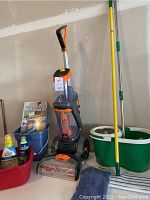 Full view of cleaner, solution bottles, brush/dustpan set, red and blue tubs, dust mop, spin mop and bucket