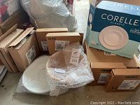 Multiple boxed and bubble-wrapped white plates and Corelle Classic 16-piece dinnerware set box