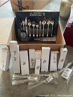 Box of J.A. Henckels International 65-piece flatware set still in packaging with multiple white boxes containing flatware pieces organized inside a larger box.