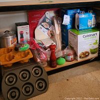 Wide view of shelf with assorted kitchen equipment including boxes and utensils