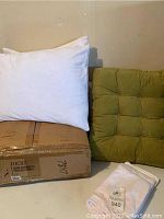 Lucid down alternative fiber bed topper boxed with three white pillows, green velvet cushion and extra pillowcases shown