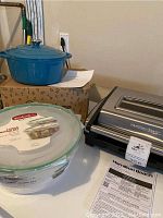 Photo showing the Hamilton Beach indoor grill in stainless steel, teal cast iron stock pot on its box labeled Pidea Home, and a round glass container from GoodCook with lid and label.