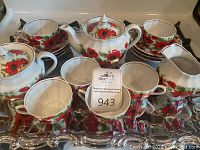 Full view of the tea set arranged on the silvertone tray showing 6 cups, 6 saucers, teapot, sugar container, and creamer all with red poppy floral motifs.