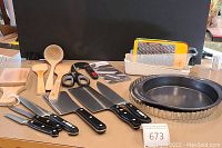 Wide view of knives, wooden utensils, tools and bakeware on counter