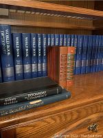 Books on wooden shelves including World Book Encyclopedia blue volumes, Time-Life Library of Art red and brown hardcover books, and several other hardcover books on second shelf.