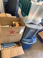Boxes stacked and filled with various books including a visible cover featuring a woman.
