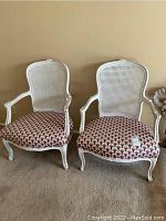 Two white wicker back armchairs side by side with patterned upholstered cushions