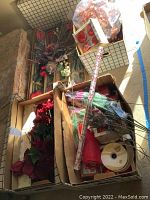 Multiple boxes filled with artificial Christmas floral decorations, ribbons and picks, all in traditional holiday colors red and green.