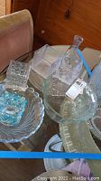 Photo showing various clear and blue glassware items on a table including bowls, vases, and a glass decanter with etched star designs.