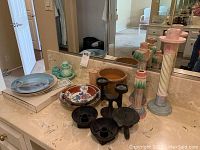 Wide view showing all plates, candle holders, and Avon collectibles arranged on marble surface in front of mirror.
