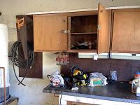 Workstation with wooden cabinets, tools, and cleaning supplies on bench and shelves