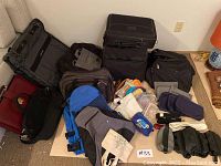 Assortment of various bags and luggage items arranged on the floor including backpacks, soft-sided luggage, and smaller pouches.
