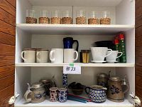 Wide shot of wooden shelving unit with four levels displaying all glassware, coffee cups, and four Goebel beer steins on bottom shelf.