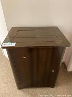 Side view of vintage wooden sewing machine table with dark finish and some wear.