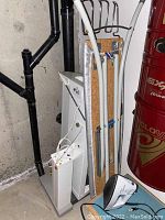Full lot items arranged in a corner showing ironing board, small table, linen press and iron.