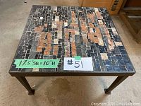 Photo of the full table showing steel frame and square mosaic tiled top with dimensions marked as 17.5" wide, 50" long, and 10" high.