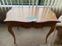 Full view of the wooden table/desk with two drawers closed, showing curved legs and wood grain pattern on top.