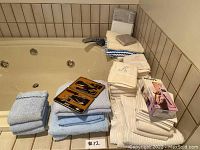 Photo of stacked blue bath towels, white and cream hand towels, boxed Philips curling iron, manicure sets in original case.
