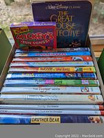 Photo of DVD collection showing titles stacked including The Great Mouse Detective, Disney Mickey's Fun Songs, and others.