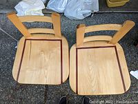 Top view showing two wooden stool seats with inlaid dark wood strips running vertically near edges, light wood seats likely maple.
