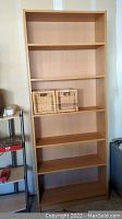 Six-shelf Ikea Billy bookcase against wall with some items nearby, baskets shown on shelf not included in sale.