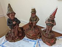 Three Tom Clark Irish themed gnome sculptures on table with Certificates of Authenticity partially visible.