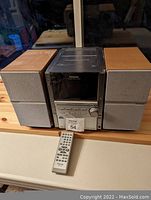 Front view of Panasonic radio CD player with two speakers and remote control on table.