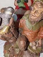 Close-up of the Zermatt gnome figurine showing detailed facial expression, clothing texture, and bird on tree stump, signed by Tom Clark on base.