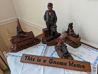 Four Tom Clark gnome sculptures grouped with their Certificates of Authenticity and a wooden sign