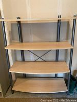 Short squat shelf with four curved wood shelves on metal frame, missing cap on top