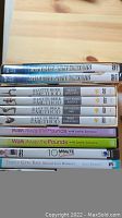 Stack of 10 workout DVDs showing titles and themes related to Yoga, Lotte Berk Method, Leslie Sansone walking program, and weight loss exercises.