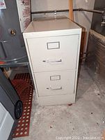 Photo showing the full front view of a beige 2 drawer Steelcase metal file cabinet with locks and label holders on each drawer.