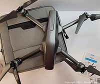 Top-down view of 4DRC quadcopter drone resting partially on a grey carrying case with instruction manual placed beside it. Propellers and scratches on drone body visible.