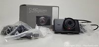 Photo of Apeman C450 dash camera alongside box and accessories including cables in plastic bags.