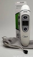 White infrared forehead and ear thermometer Model FC-IR1T with original box and gray storage pouch visible.