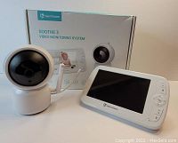 White PTZ baby monitor camera and white 5-inch LCD handheld monitor with the original product box in the background