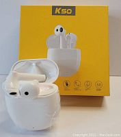 Pair of white K50 wireless earbuds displayed with open white charging case in front of bright yellow box featuring product image and icons showing touch controls, Bluetooth 5.0, wireless call support, HD sound quality.