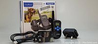 Photo of PetMaster rechargeable and waterproof pet training collar set with collar, remote control, charger base, USB cable, and original box showing a dog on the front.