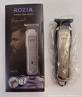 Photo showing Rozia Professional Hair Trimmer in metallic silver color next to its branded packaging box labeled HQ278. The packaging has an image of a male with styled hair and product name and specifications.